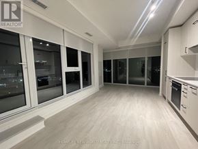 Toronto (Banbury-Don Mills) condo for rent - A spacious kitchen with white cabinets and a large window overlooking a cityscape.