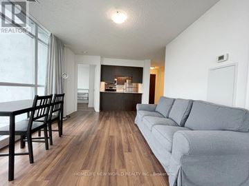 Toronto (Bendale) condo for rent - A living room with a grey couch and a dining table.