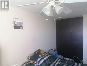 Mississauga (Mississauga Valleys) condo for rent - A bedroom with a bed covered in a plaid comforter and a ceiling fan above it.