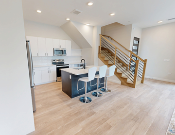 Wheaton apartment for rent - A kitchen with a bar stool and a staircase.