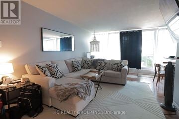 Toronto (Victoria Village) condo for rent - A living room with a white couch and a large window.