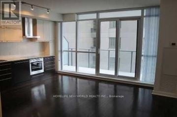 Toronto (Bay Street Corridor) condo for rent - A modern kitchen with dark wood floors and a large window.