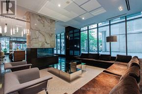 Toronto (Bay Street Corridor) condo for rent - A modern living room with a stone fireplace and a long wooden table.