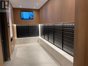 Toronto (Agincourt South-Malvern West) condo for rent - A hallway with a row of lockers on the right and a TV mounted on the wall.