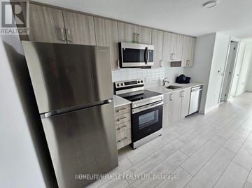 Toronto (Yorkdale-Glen Park) condo for rent - A modern kitchen with a stainless steel refrigerator and microwave above the stove.