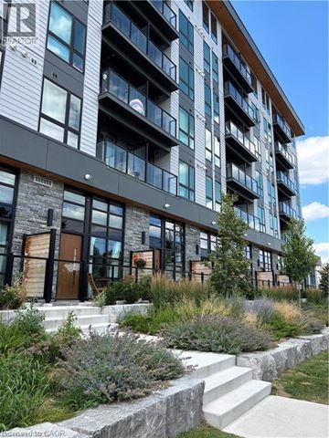 Waterloo condo for rent - A modern building with a stone entrance and a landscaped area in front.