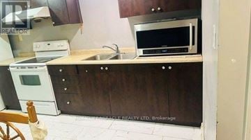 Brampton (Madoc) apartment for rent - A kitchen with a white oven and a black microwave above a counter.