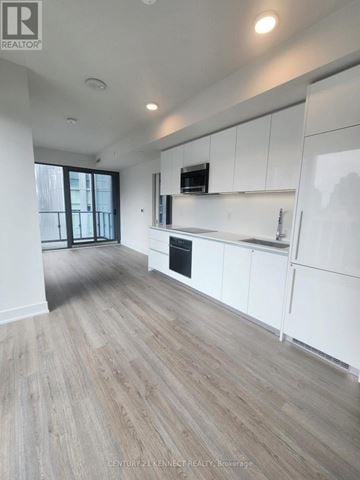 Toronto (Annex) condo for rent - A spacious kitchen with white cabinets and a wooden floor.