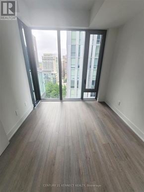 Toronto (Annex) condo for rent - A room with wooden flooring and a view of the city through large windows.