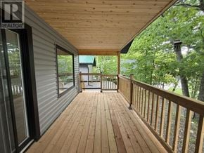 Heyden apartment for rent - A wooden deck with a metal railing and a glass door leading to a porch.