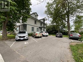 Welland (Welland Downtown) multi-family for rent - A parking lot with cars and a house in the background.