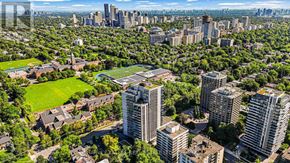 Toronto (Forest Hill South) condo for rent - A cityscape with a mix of residential and commercial buildings, surrounded by lush greenery.