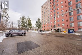 Waterloo multi-family for rent - A parking lot in front of a red building with a grey car parked in the foreground.