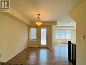 Toronto (Clairlea-Birchmount) townhouse for rent - A well-lit room with a wooden floor and a glass door leading to another room.