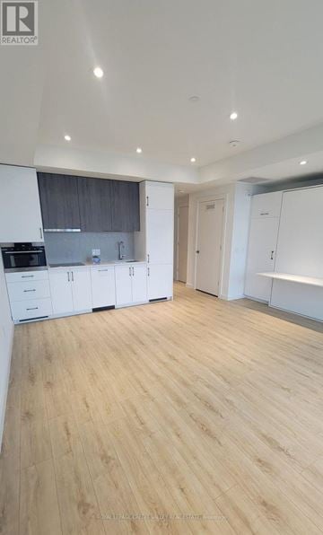 Kitchener condo for rent - A kitchen with white cabinets and a wooden floor.
