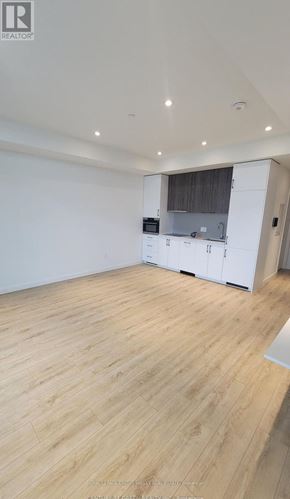 Kitchener condo for rent - A spacious room with wooden flooring and white walls.