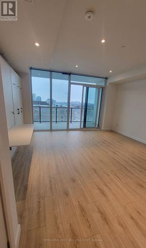 Kitchener condo for rent - A spacious room with wooden flooring and a large window overlooking a cityscape.