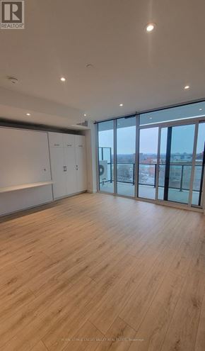 Kitchener condo for rent - A spacious room with wooden flooring and large windows.