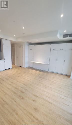 Kitchener condo for rent - A spacious room with wooden flooring and white cabinetry.
