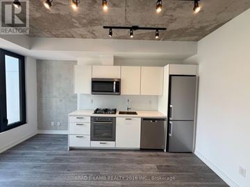Toronto (Moss Park) condo for rent - A kitchen with white cabinets and a stainless steel refrigerator.