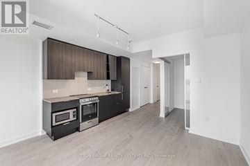 Mississauga (City Centre) condo for rent - A modern kitchen with dark wood cabinets and stainless steel appliances.
