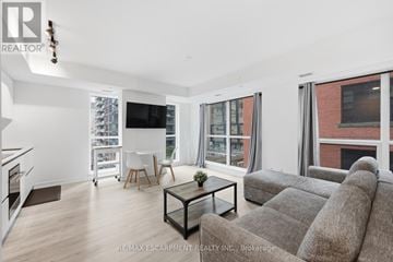 Toronto (Waterfront Communities) condo for rent - A living room with a grey couch and a glass coffee table.