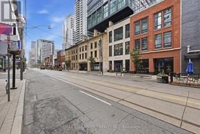 Toronto (Waterfront Communities) condo for rent - A city street with buildings on either side and a clear blue sky.