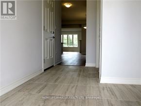 Niagara Falls (Lyons Creek) apartment for rent - A hallway with a wooden floor and white walls leading to a door.