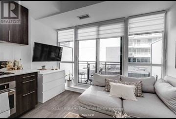 Toronto (Waterfront Communities) condo for rent - A modern living room with a grey couch and a kitchen area with wooden cabinets.