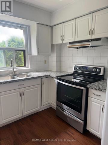 Richmond Hill (Harding) triplex for rent - A kitchen with white cabinets and a stove top oven.