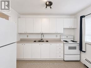 Mississauga (Applewood) condo for rent - A white kitchen with a sink, stove, and cabinets.