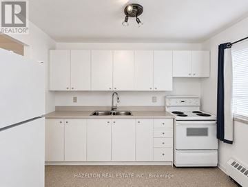 Mississauga (Applewood) condo for rent - A white kitchen with a sink, stove, and cabinets.