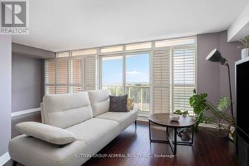Toronto (Waterfront Communities) condo for rent - A living room with a white sofa and a table with a plant on it.
