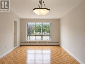 Mississauga (Applewood) condo for rent - A room with a large window and a view of trees and a parking lot.