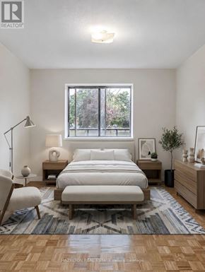 Mississauga (Applewood) condo for rent - A bedroom with a large bed, a chair, and a window with a view of trees.