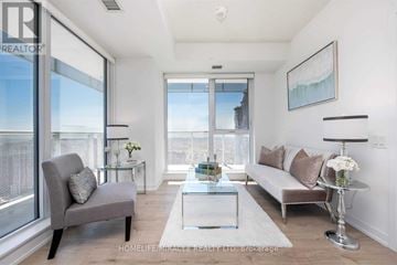 Mississauga (City Centre) condo for rent - A living room with a grey sofa, a grey armchair, a glass coffee table, and a painting on the wall.