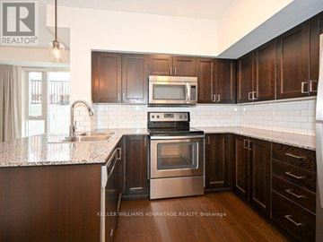 Toronto (Dovercourt-Wallace Emerson-Junction) townhouse for rent - A kitchen with dark wood cabinets and a stainless steel oven.