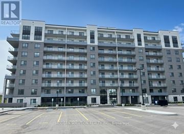 Guelph (Grange Road) condo for rent - A large apartment building with a parking lot in front.