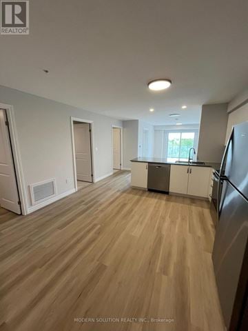 Guelph (Grange Road) condo for rent - A spacious kitchen with wooden flooring and white walls.