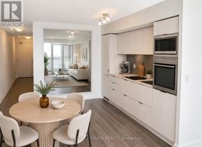 Toronto (Waterfront Communities) condo for rent - A modern kitchen with white cabinets and a dining table with chairs.
