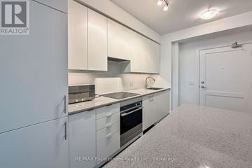 Mississauga (Fairview) condo for rent - A kitchen with white cabinets and appliances in a room with a white door.