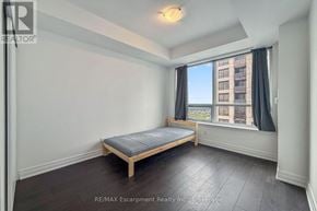 Mississauga (Fairview) condo for rent - A bedroom with a bed, window, and wooden floors.