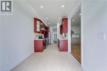 Mississauga apartment for rent - A spacious kitchen with red cabinets and a white floor.