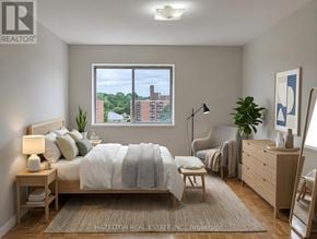 Mississauga (Applewood) condo for rent - A bedroom with a bed, chair, and a window overlooking a building.