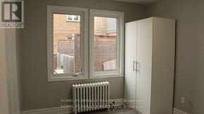 Toronto (New Toronto) multi-family for rent - A room with a window, a radiator, and a white cupboard.