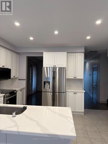Brampton (Sandringham-Wellington) apartment for rent - A modern kitchen with white cabinets and a marble countertop.