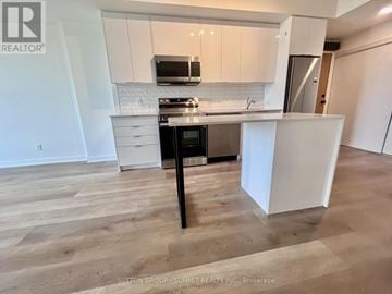 Brantford condo for rent - A kitchen with white cabinets and a black island.