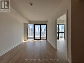 Mississauga (City Centre) condo for rent - A spacious room with wooden floors and large windows overlooking a cityscape.