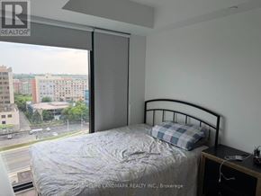 Mississauga (Cooksville) condo for rent - A bedroom with a bed, nightstand, and window overlooking a cityscape.