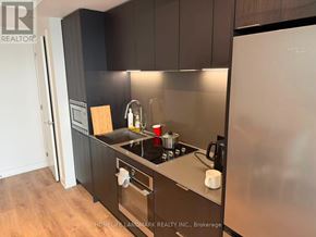 Mississauga (Cooksville) condo for rent - A modern kitchen with dark wood cabinets and stainless steel appliances.